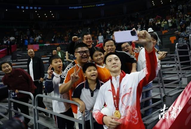 11月12日,十五运会男篮成年组决赛,广东队获得冠军后,胡明轩与球迷们合影留念。张由琼 摄