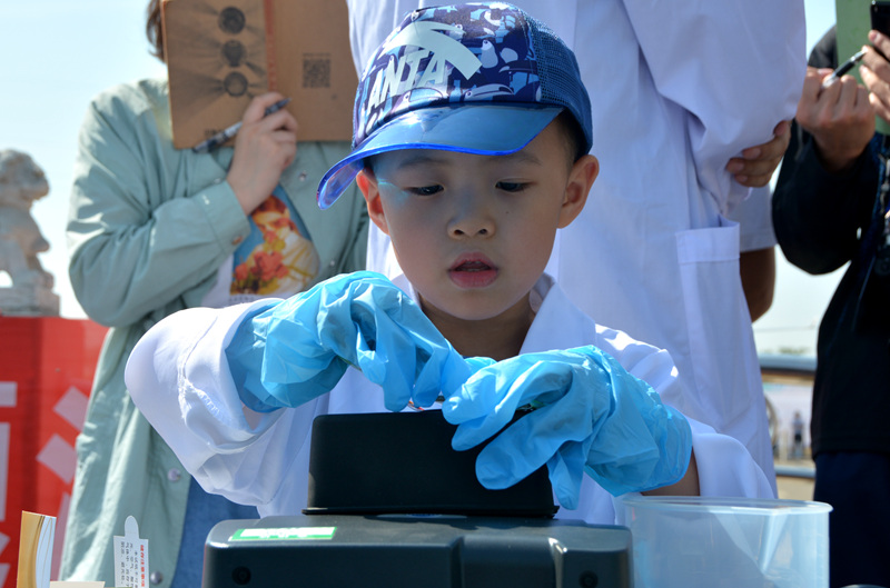 崔晋嘉小朋友对水样检测十分感兴趣，他从小就知道这个工作叫做“做样”，今天终于自己操作了一次。韩晓东说，最近儿子迷上了一本叫做《南水奇游记》的漫画绘本，讲的都是南水北调的故事，每天晚上要让自己念上一段才能入睡。（人民网记者孙博洋摄）