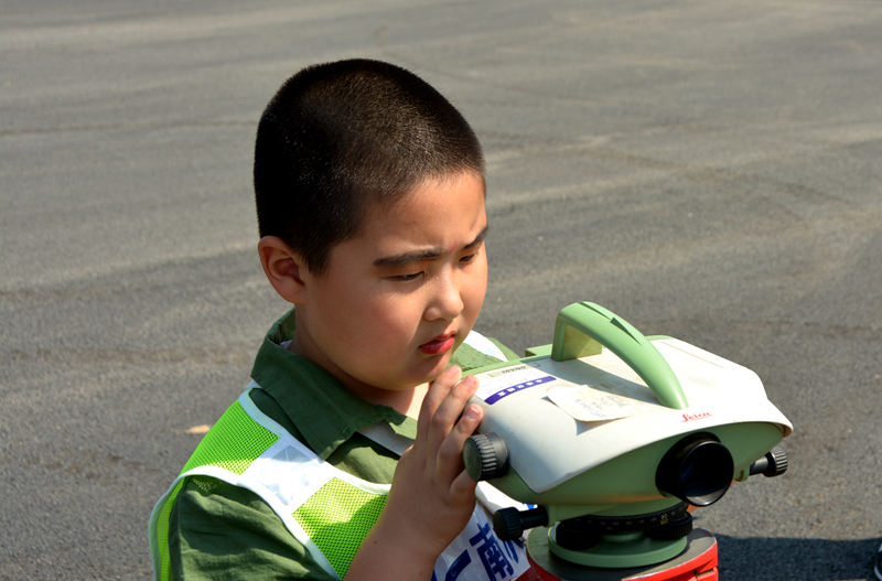 潘禹辰小朋友独立操作测绘仪器。潘禹辰说爸爸经常给自己讲南水北调是事情，自己为有一位南水北调工程师的爸爸感到骄傲。（人民网记者孙博洋摄）