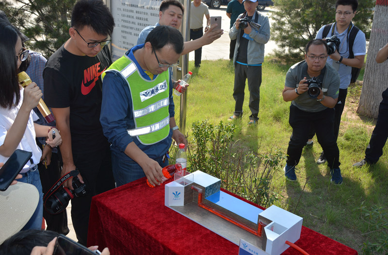工作人员正在用模型演示“倒虹吸”的工作原理，引起媒体记者们的极大兴趣。（人民网记者孙博洋摄）