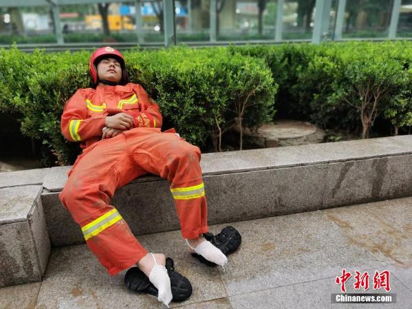 在水中浸泡多个小时的消防员脱掉鞋子就地休息.宜昌消防供图
