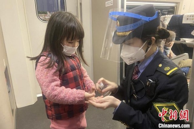 图为1月18日，南昌客运段G2777次列车长姚珊珊在为小朋友戴好口罩。　郑璐瑶 摄