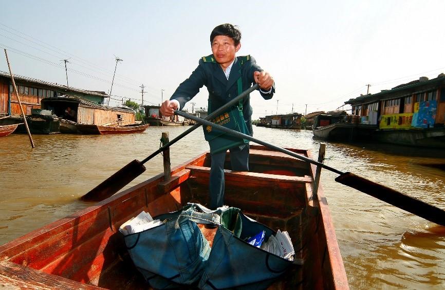 2013年,水上郵路投遞員唐真亞划著小木船在湖區投遞.劉春平攝