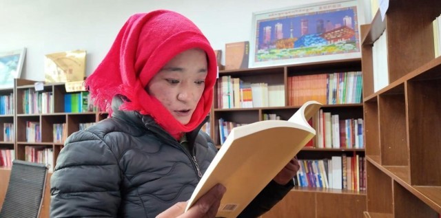 一名妇女正在认真阅读书籍。申扎县融媒体中心供图