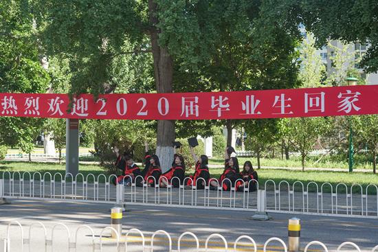 7月4日,中国人民大学校内,返校的2020届毕业生在校门处的横幅下喊影